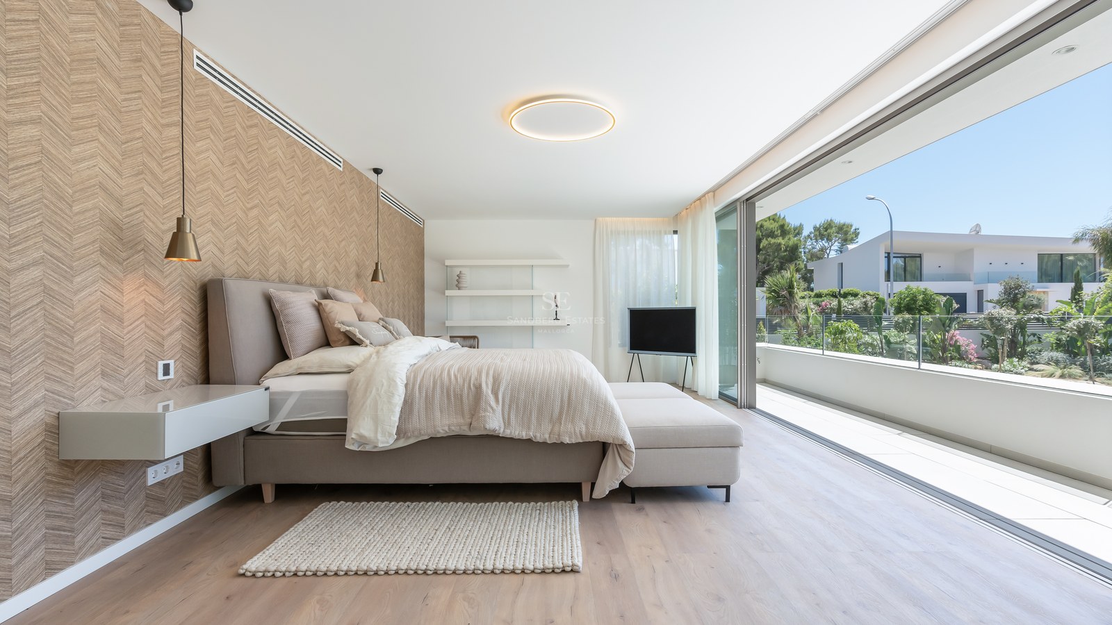 Modern bedroom with floor-to-ceiling glass doors opening to a terrace, neutral tones, and chevron-patterned accent wall.