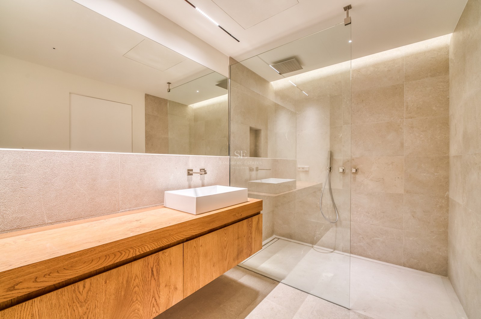 Salle de bain moderne avec meuble en chêne suspendu, vasque blanche, grand miroir et douche à l'italienne vitrée.