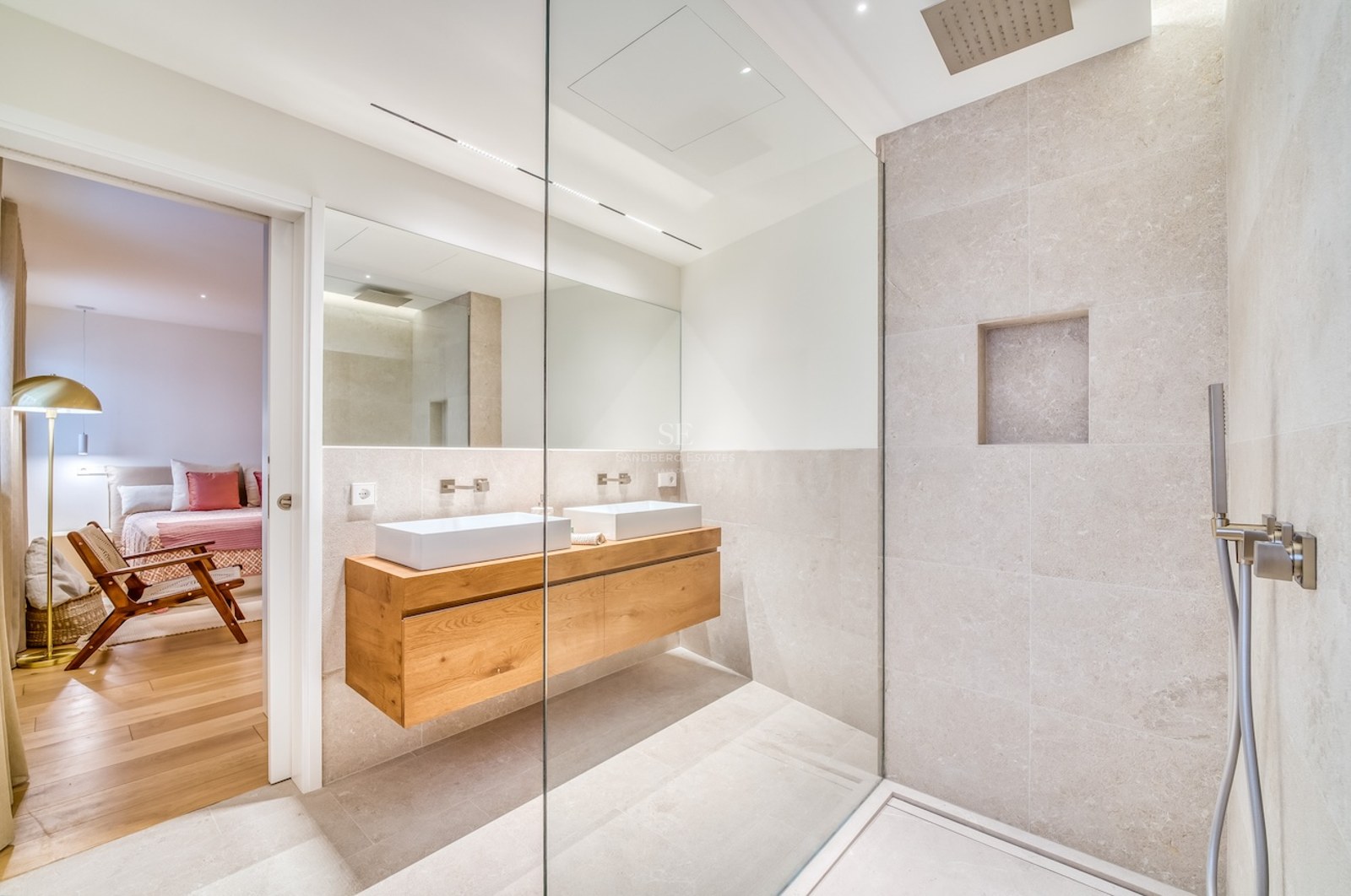 Salle de bains moderne avec douche à l'italienne, double vasque sur meuble en bois et carrelage en pierre beige.