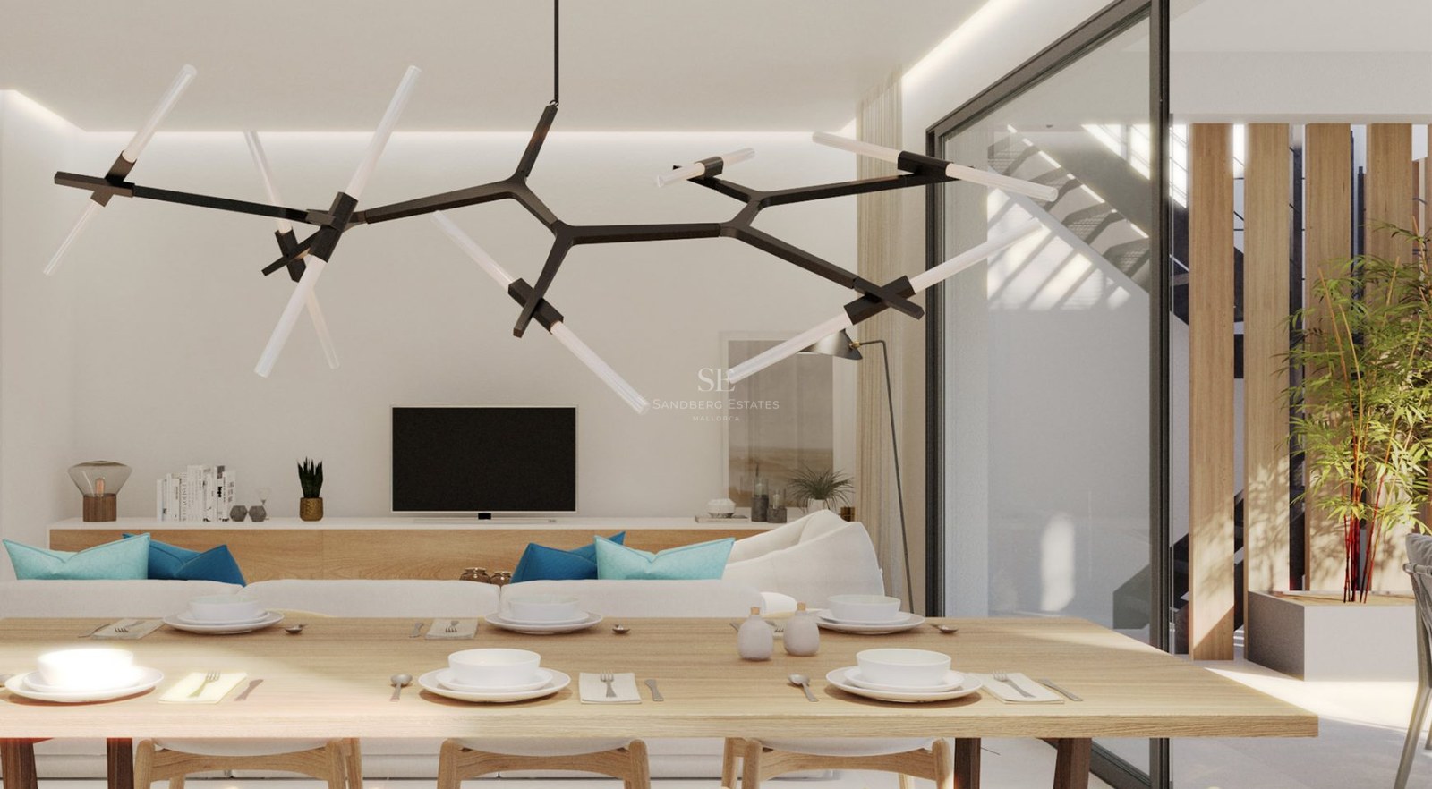 Modern dining area with a light wood table and designer chandelier, overlooking a white sofa and bright interior.
