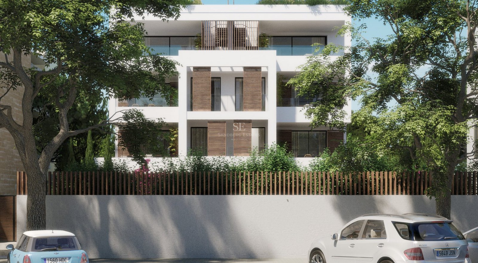 Front view of a white modern multi-story apartment building with wooden shutters, glass balconies, and lush greenery.