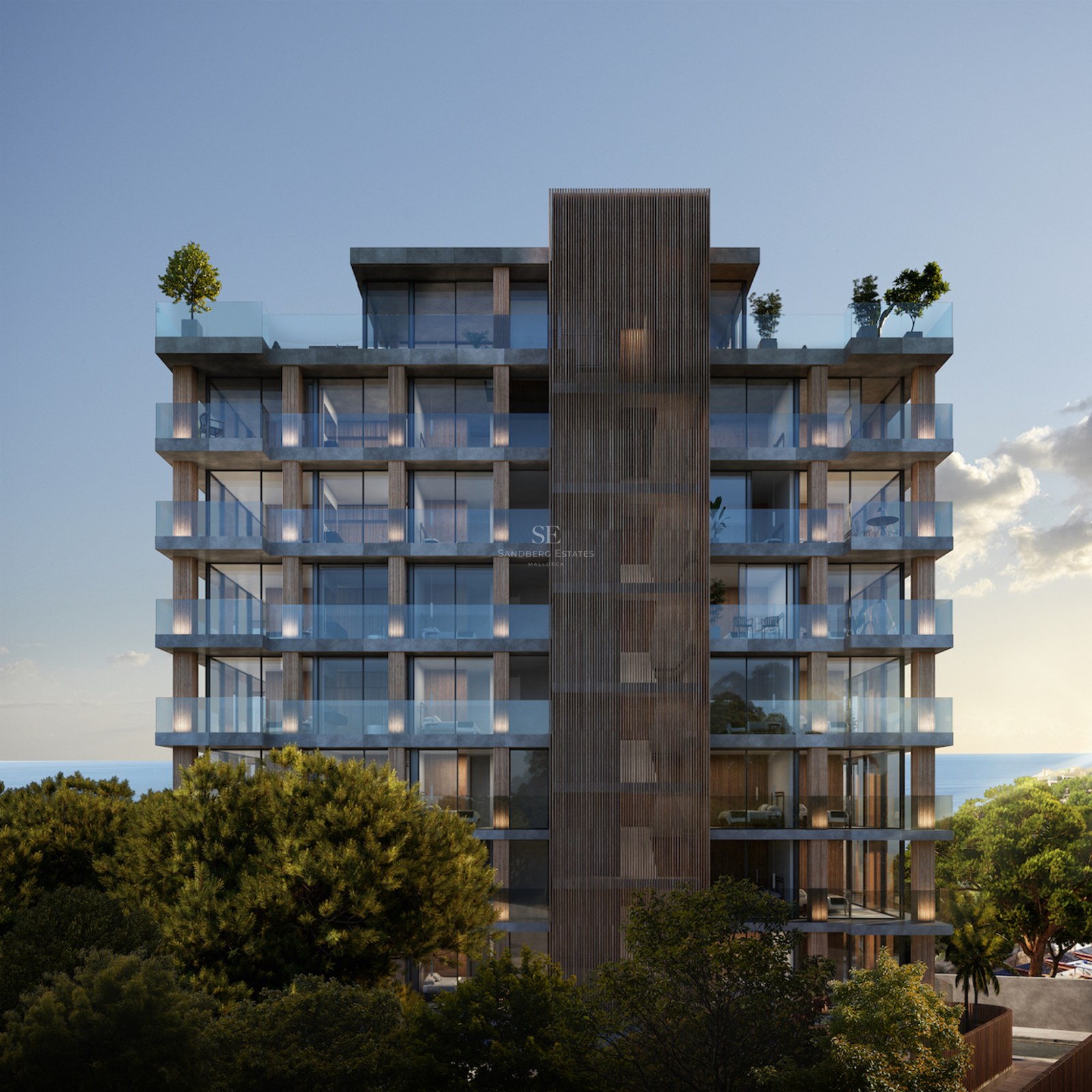 Modern multi-story building with glass balconies and wood accents surrounded by trees and sea views.