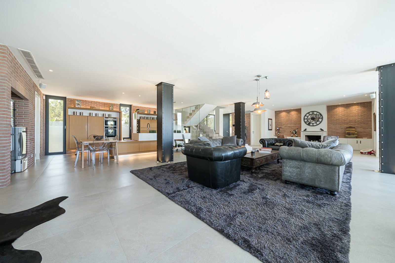 Vaste salon avec baies vitrées, piscine reflétant la lumière, design moderne, canapés en cuir et table basse élégante. Éclairage naturel.