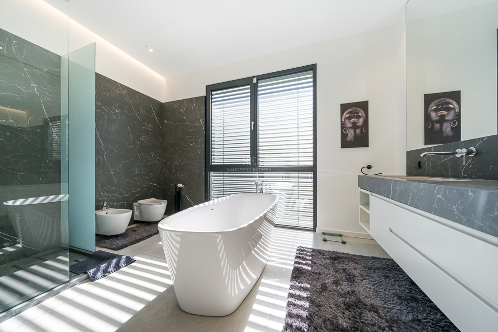 Vue de la villa avec piscine à débordement, chaises longues et végétation luxuriante. Design moderne avec de grandes fenêtres et des couleurs claires.