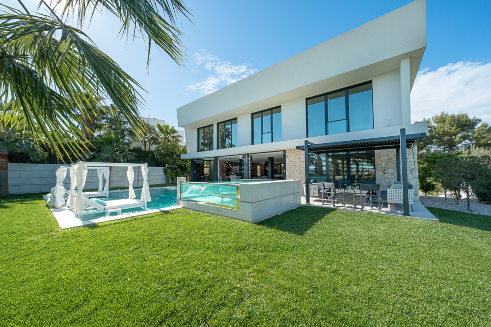 Vaste salon avec baies vitrées, vue sur mer, parquet clair, cheminée et mobilier moderne dans des tons neutres.