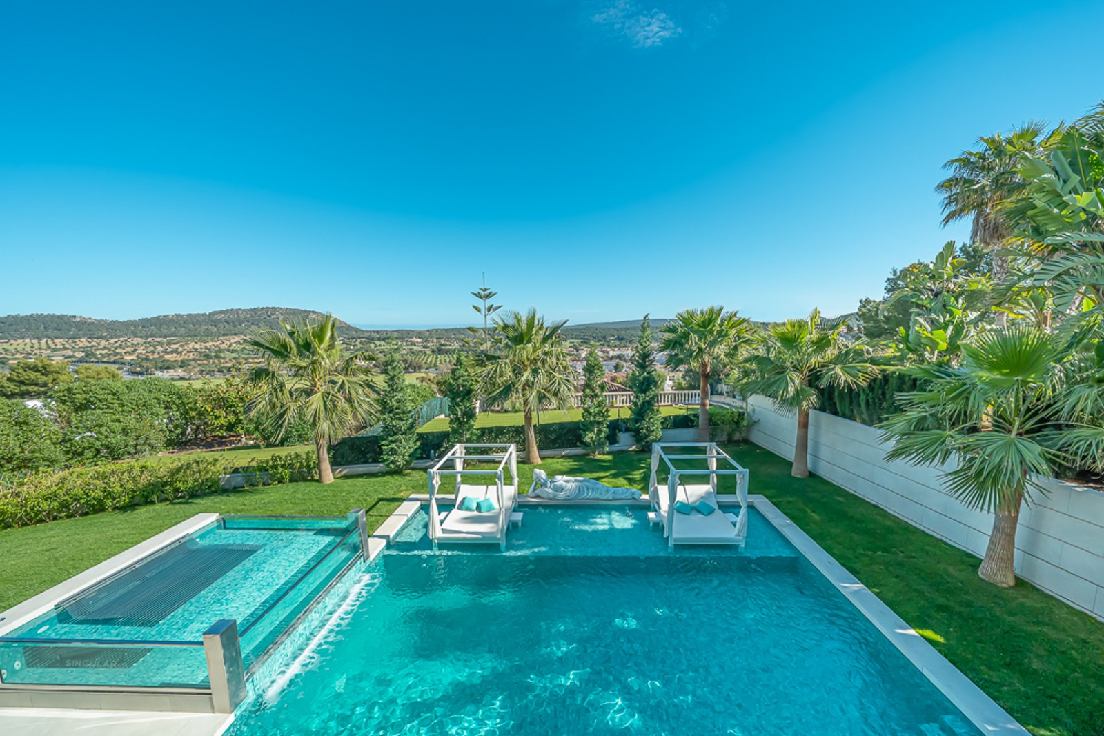 Grand balcon avec vue sur la mer. Mobilier d'extérieur élégant avec fauteuils et table basse. Garde-corps en verre maximisant la vue panoramique.