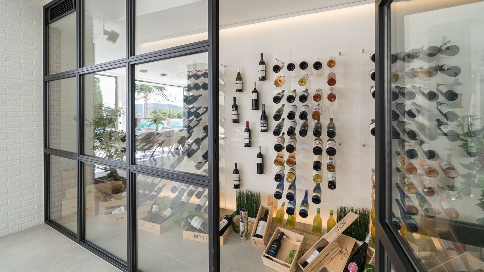 Cave à vin moderne vitrée avec cadres noirs, bouteilles sur supports minimalistes et caisses en bois.
