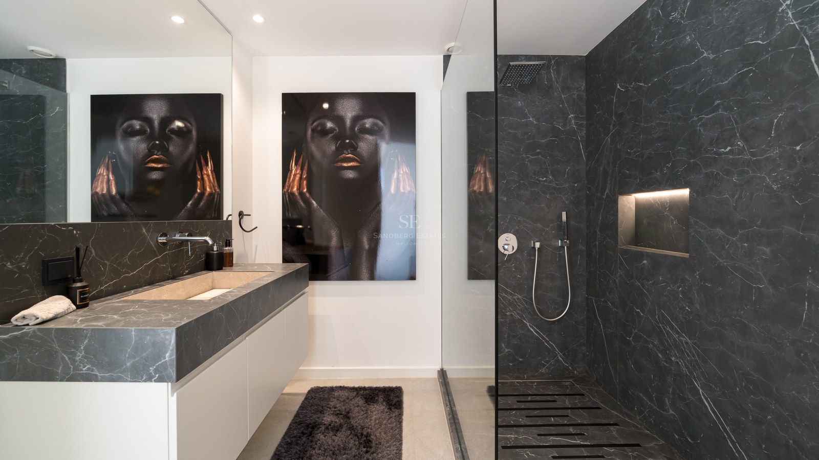 Salle de bain contemporaine avec murs en marbre sombre, douche en verre et vasque intégrée en pierre.