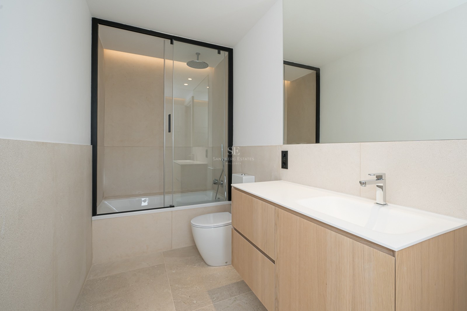 Modernes Bad mit schwebendem Eichen-Waschtisch, Steinfliesen und Badewanne mit schwarzer Glastrennwand.