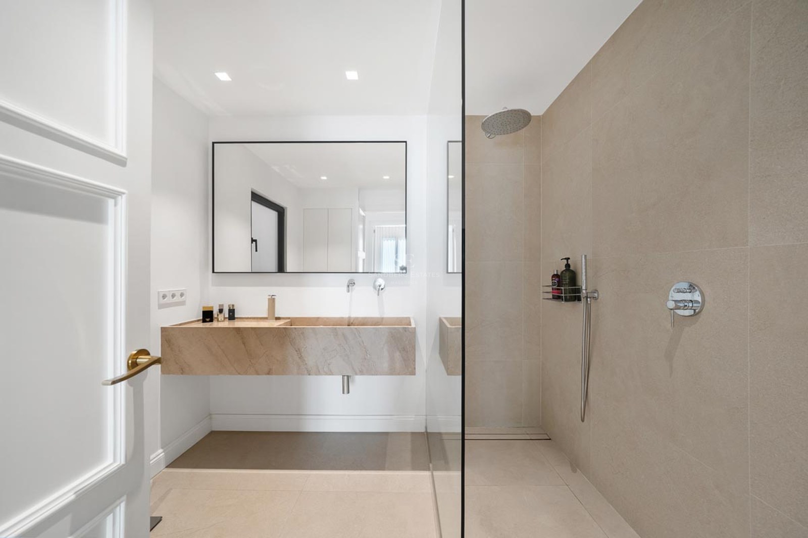 Salle de bain moderne avec vasque suspendue en pierre, grand miroir et douche à l'italienne.
