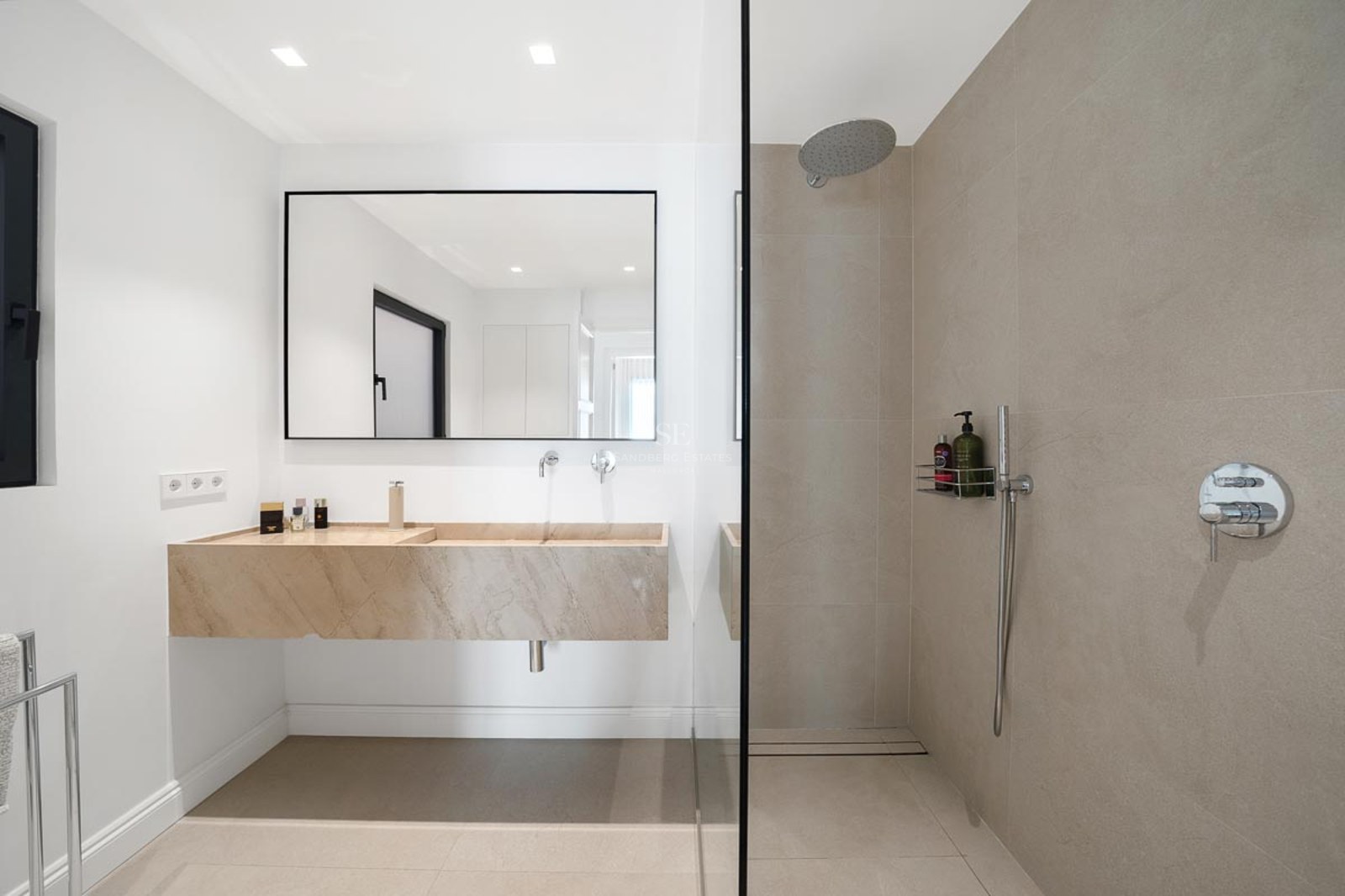 Salle de bain moderne avec vasque suspendue en pierre, grand miroir à cadre noir et douche à l'italienne vitrée.