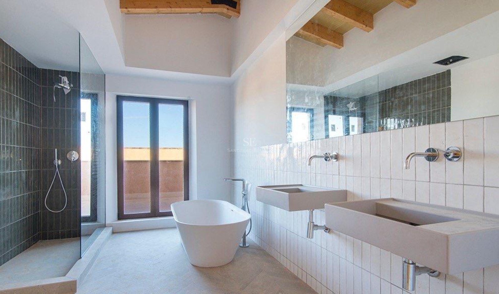 Minimalist bathroom featuring dual stone sinks, a white freestanding bathtub, and walk-in shower under wooden beams.