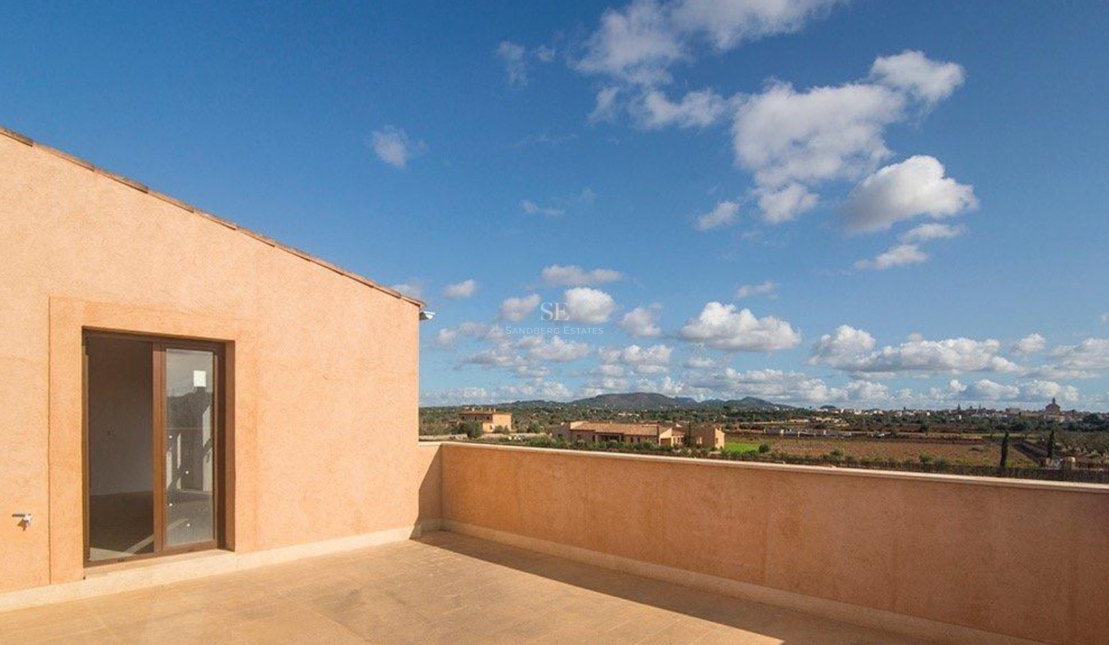 Spacious rooftop terrace featuring natural stone tiling, ochre walls, and sweeping views of the Mediterranean landscape.