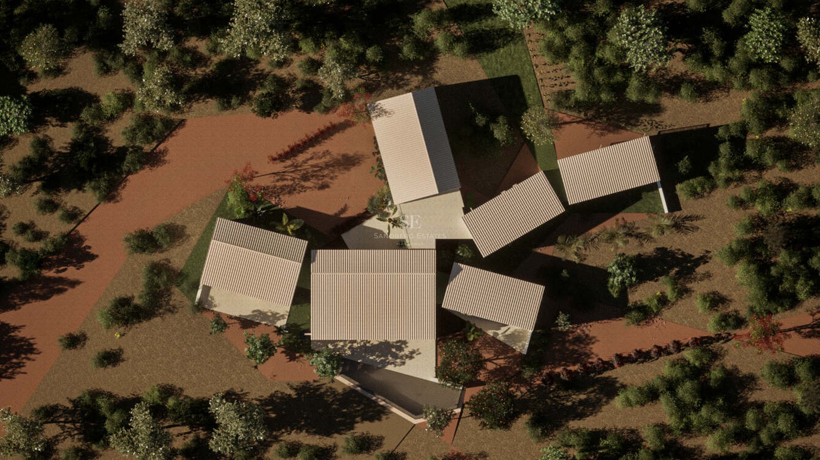 Bird's eye view of a contemporary villa with multiple pitched roofs surrounded by dense green Mediterranean trees.
