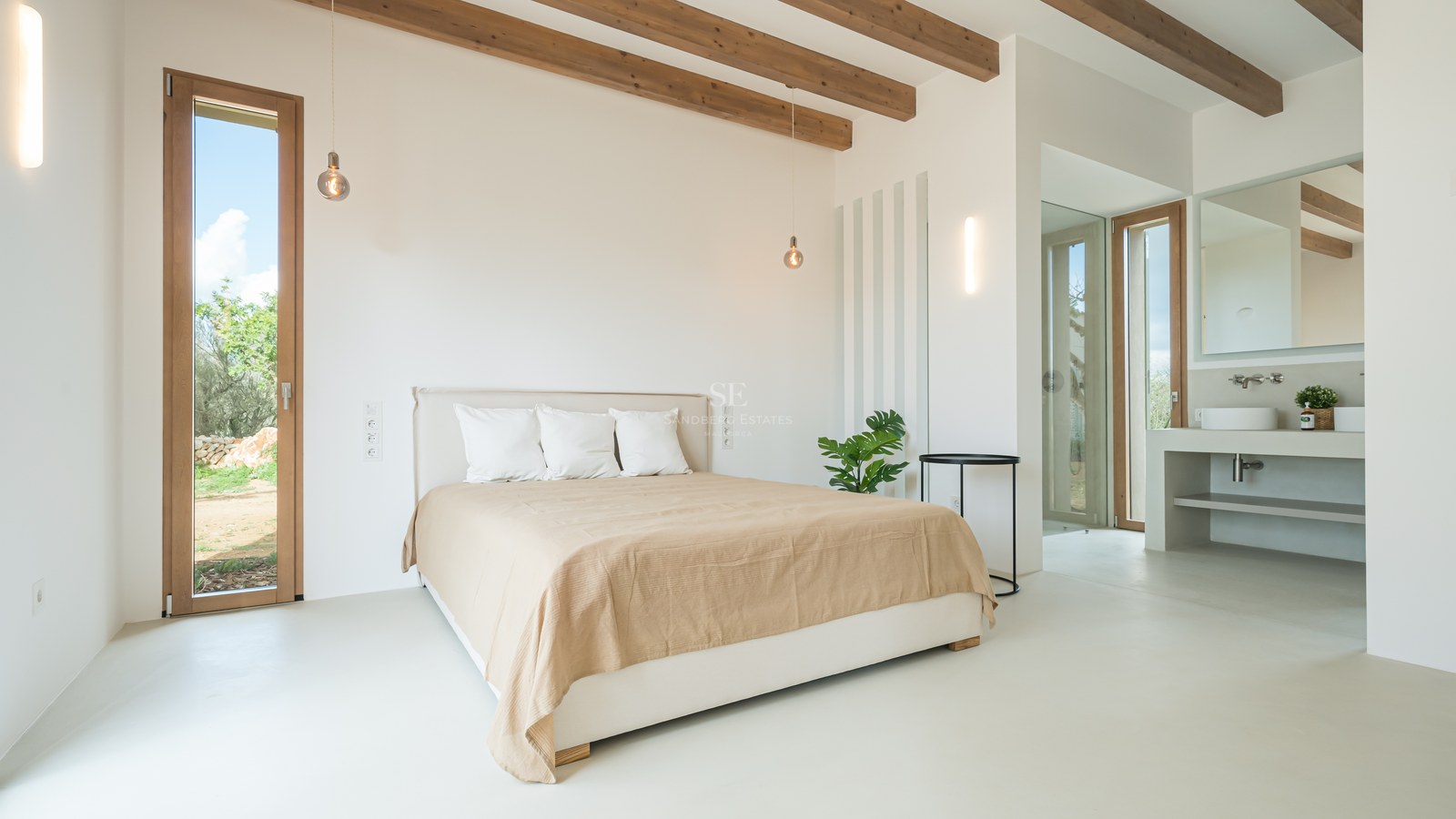 Minimalist bedroom featuring exposed wooden ceiling beams, white microcement floors, and en-suite bathroom.