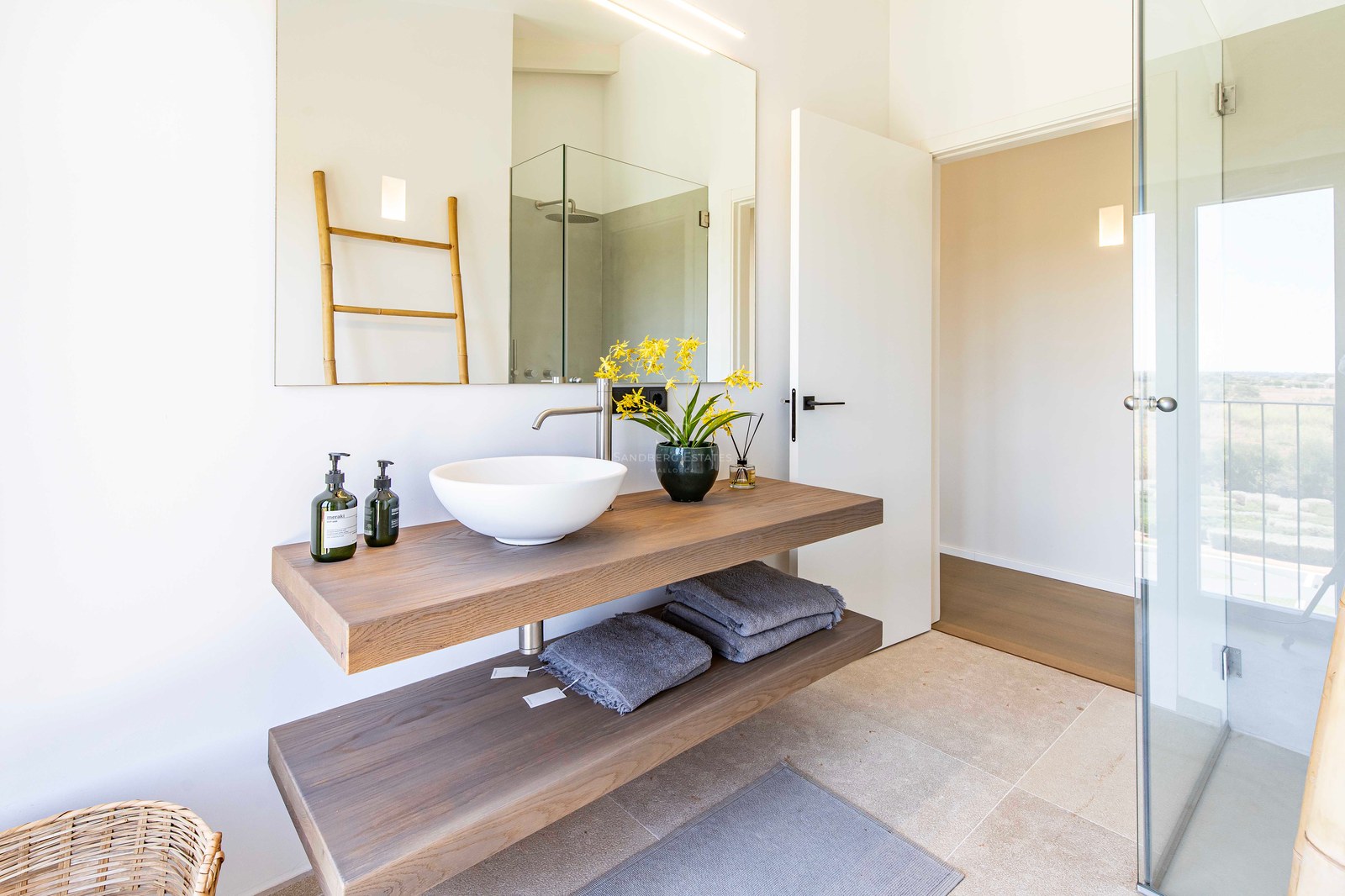 Salle de bain minimaliste avec meuble en chêne suspendu à deux niveaux, vasque blanche et grand miroir mural.