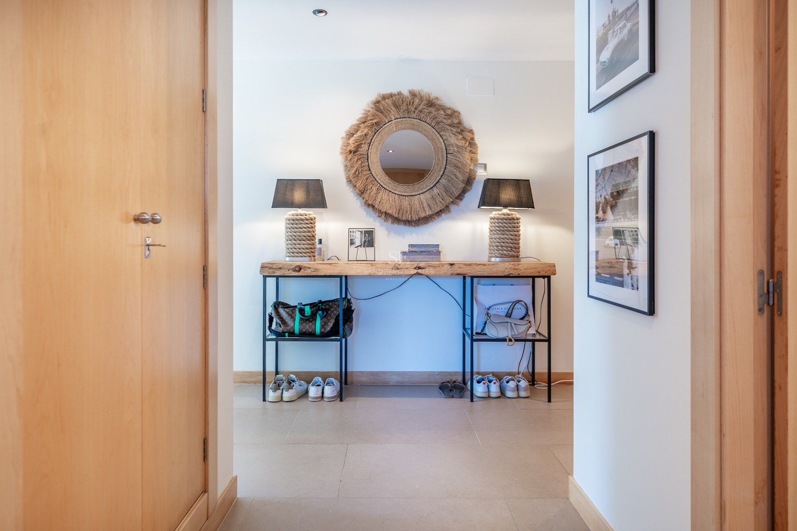 Hallway featuring a live-edge wood console table, sunburst mirror, and rope lamps on a light stone floor.