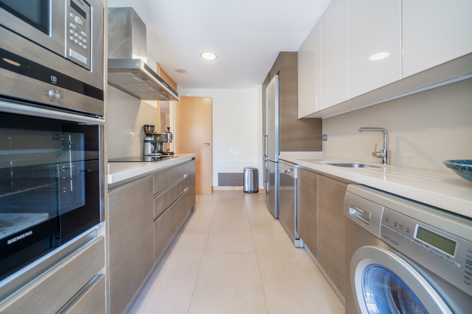 Galley-style kitchen featuring Siemens appliances, wood-grain lower cabinets, and white high-gloss upper cabinets.