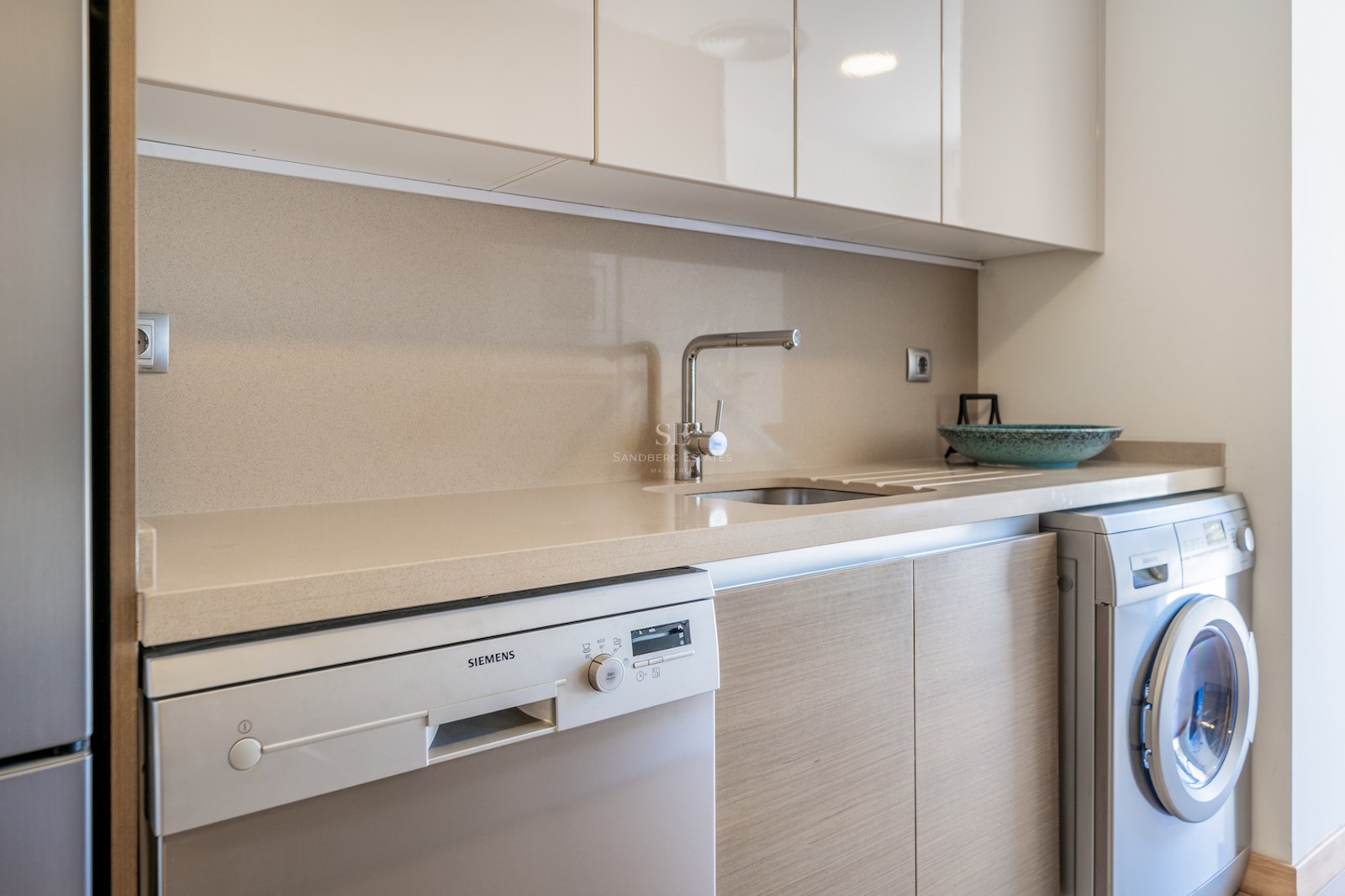 Modern utility area featuring a quartz countertop, stainless steel sink, and integrated Siemens appliances.