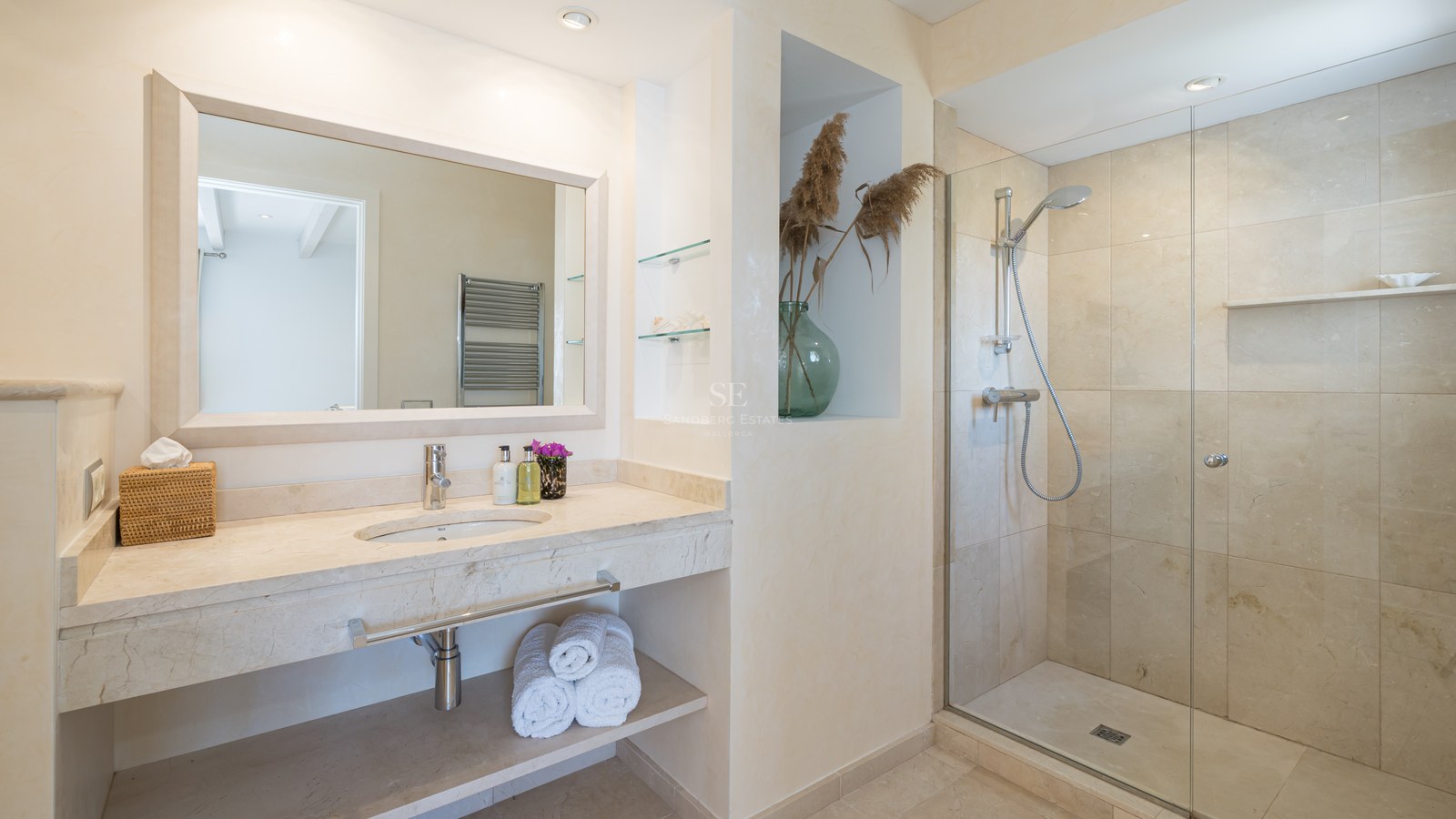 Salle de bain moderne avec douche à l'italienne, vasque en marbre beige et grand miroir à cadre blanc.