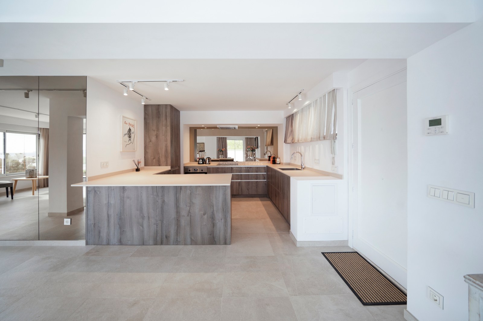 Cocina moderna con armarios de efecto madera gris, encimeras de piedra beige y suelos de gres porcelánico.