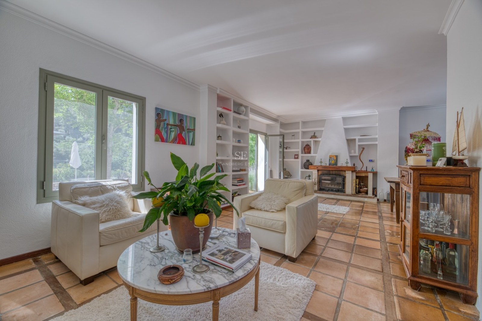 Salon spacieux avec fauteuils en cuir, table en marbre et cheminée sur un sol traditionnel en terre cuite.