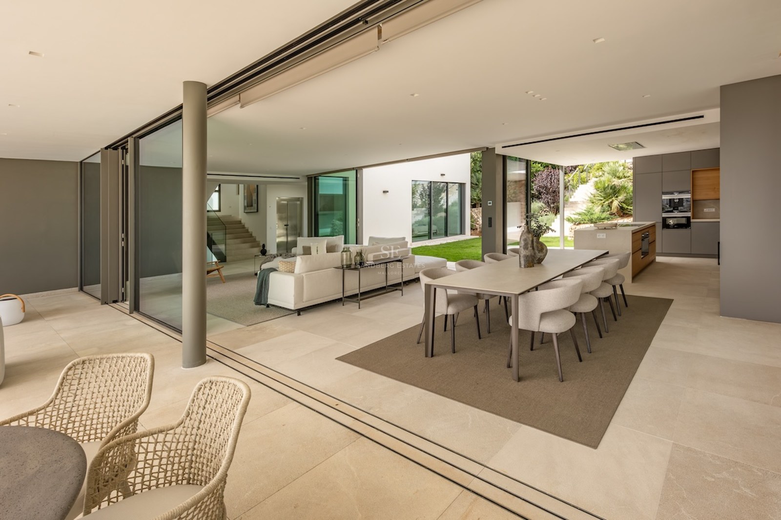 Modern open-plan living and dining room with large sliding glass doors opening to a sunlit garden.