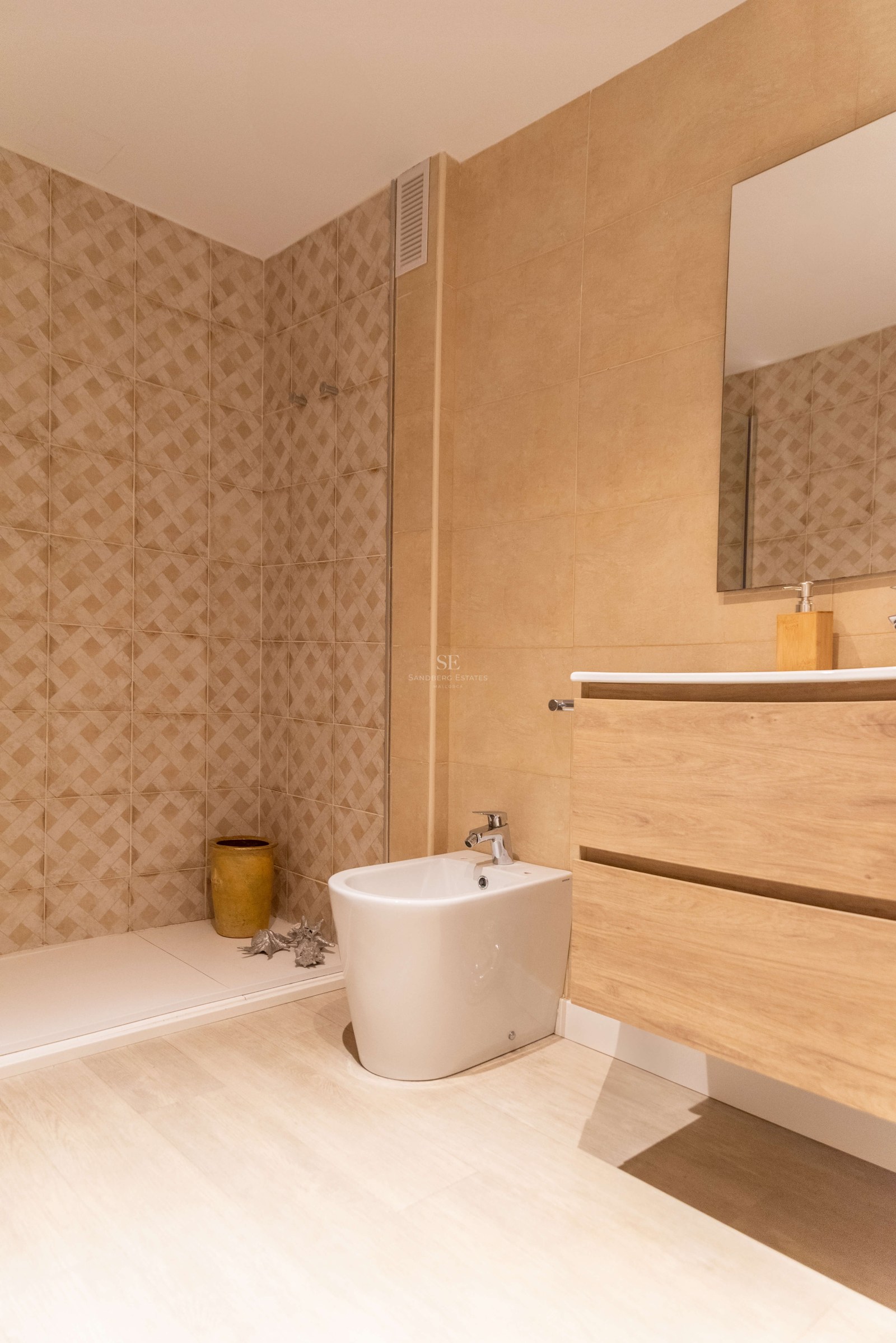 Salle de bain contemporaine avec carrelage tons sable, douche à l'italienne, meuble vasque en bois et bidet blanc.