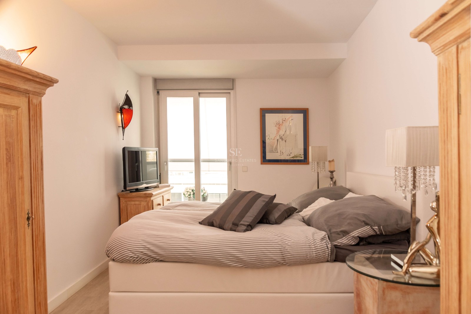 Chambre à coucher avec un grand lit, des meubles en bois, des lampes en cristal et un balcon attenant.