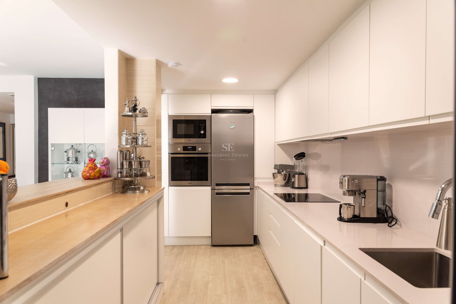 Cuisine moderne épurée avec placards blancs, appareils en acier inoxydable et comptoir en bois clair.