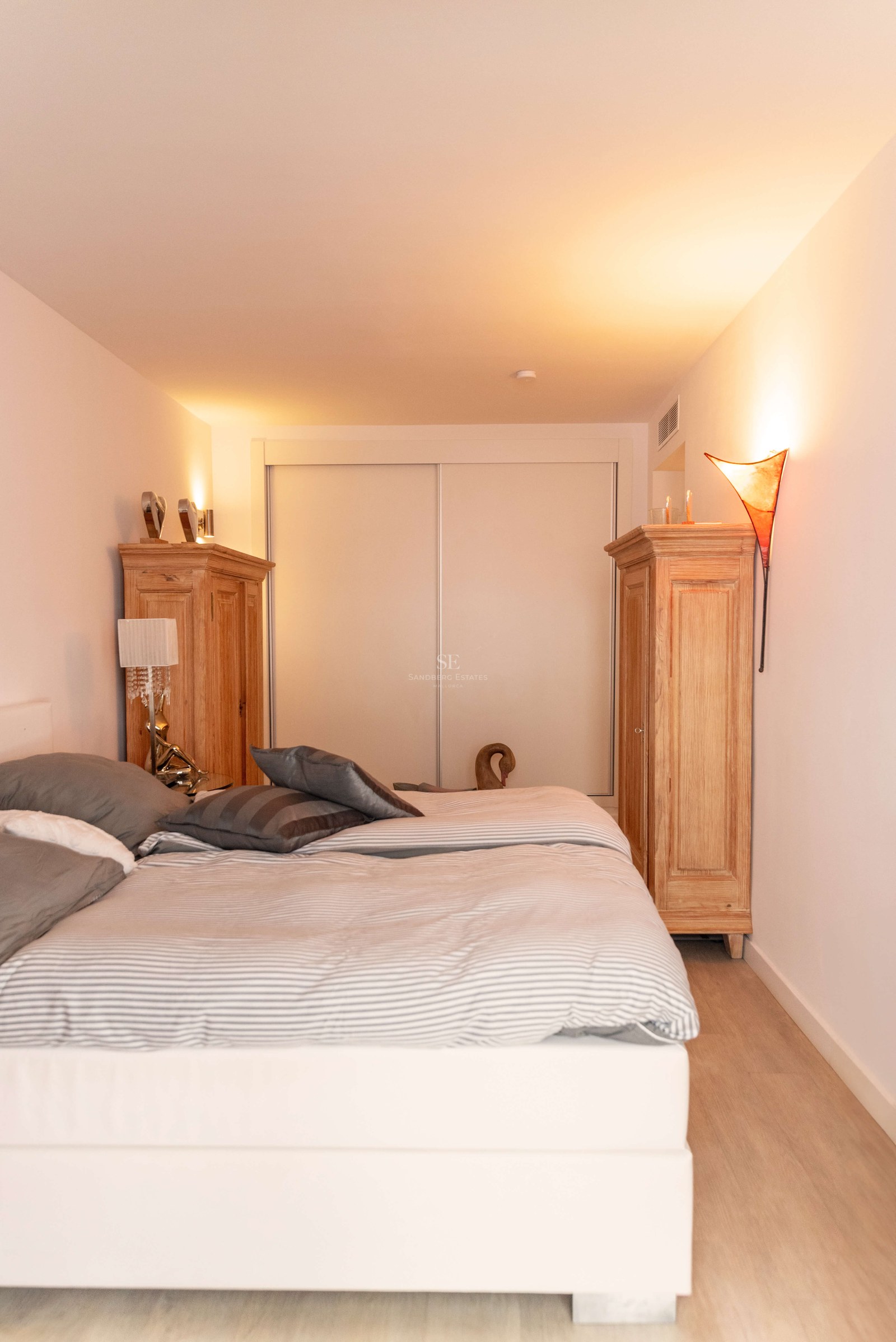 Chambre lumineuse avec grand lit, deux armoires en bois et placards intégrés sous un éclairage d'ambiance chaleureux.