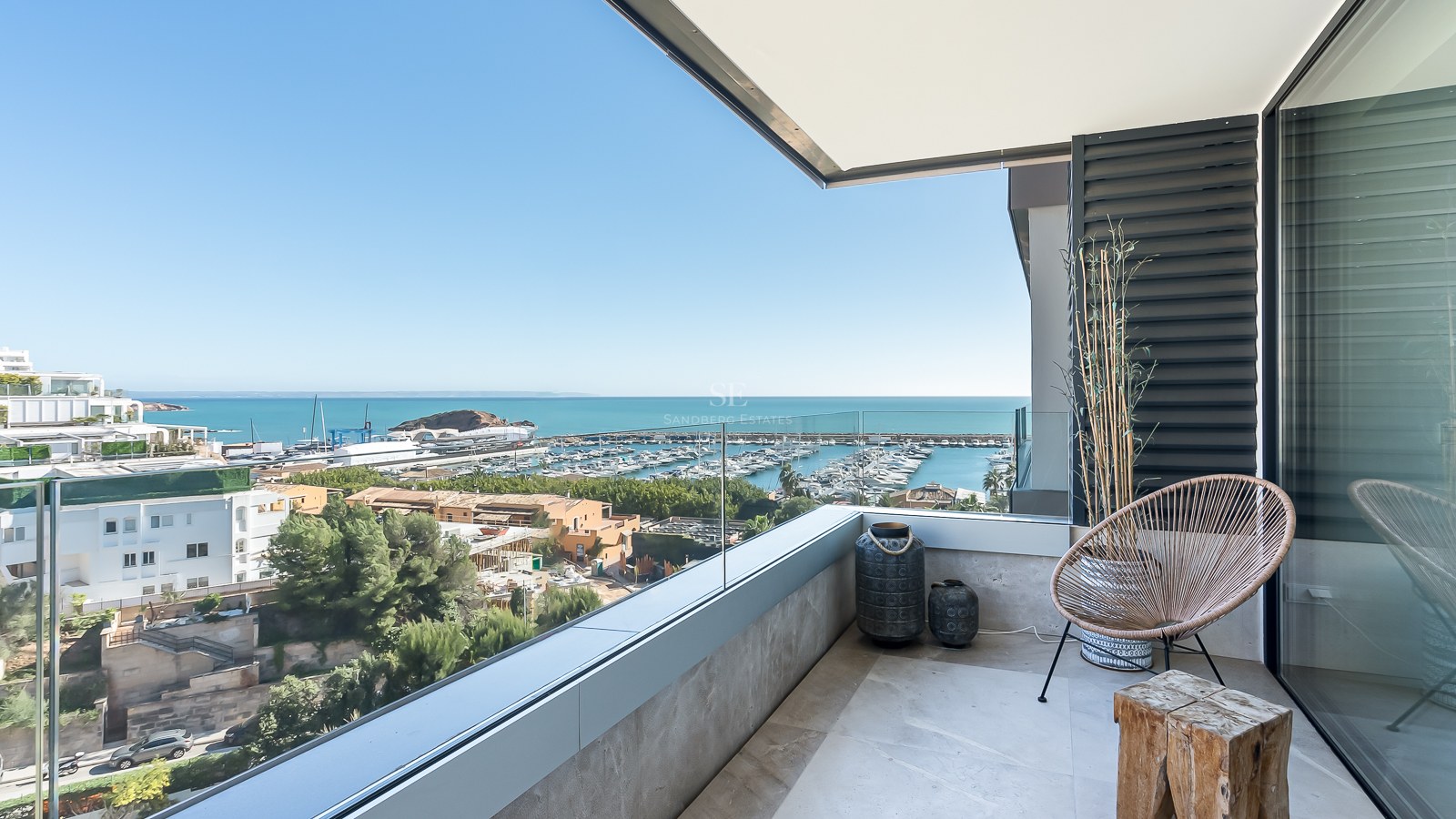 Balcon contemporain avec garde-corps en verre surplombant un port de plaisance et la mer Méditerranée.