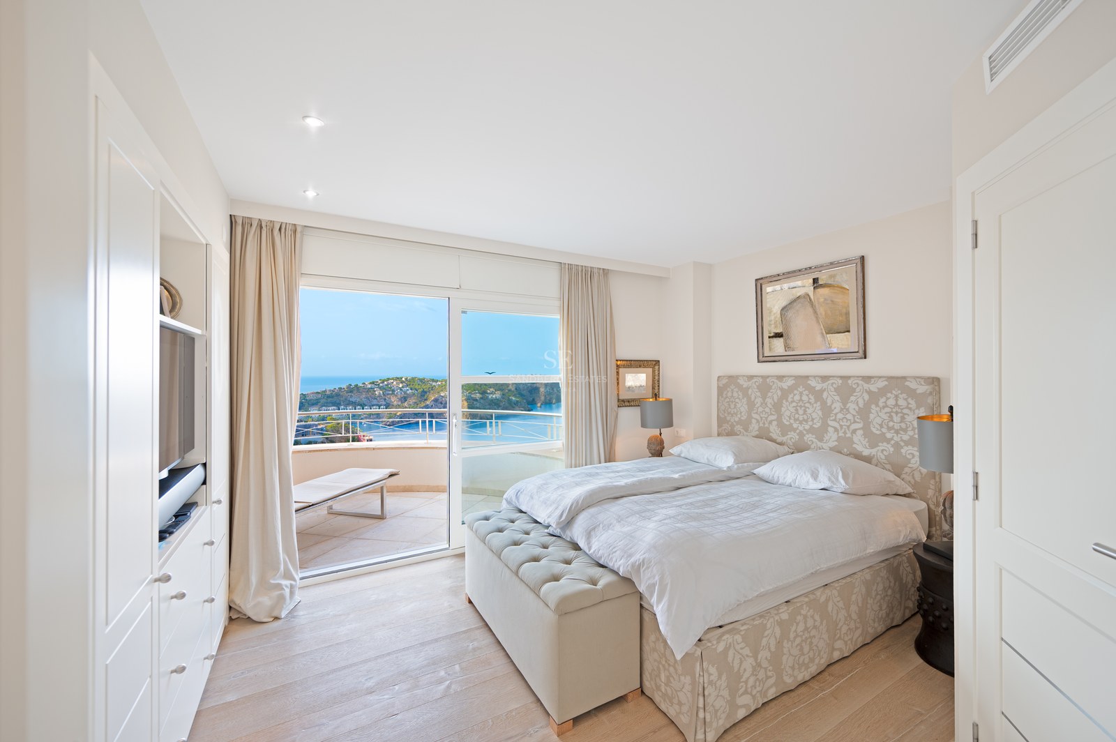 Bright master bedroom featuring a double bed with upholstered headboard and large sliding glass doors opening to a terrace.