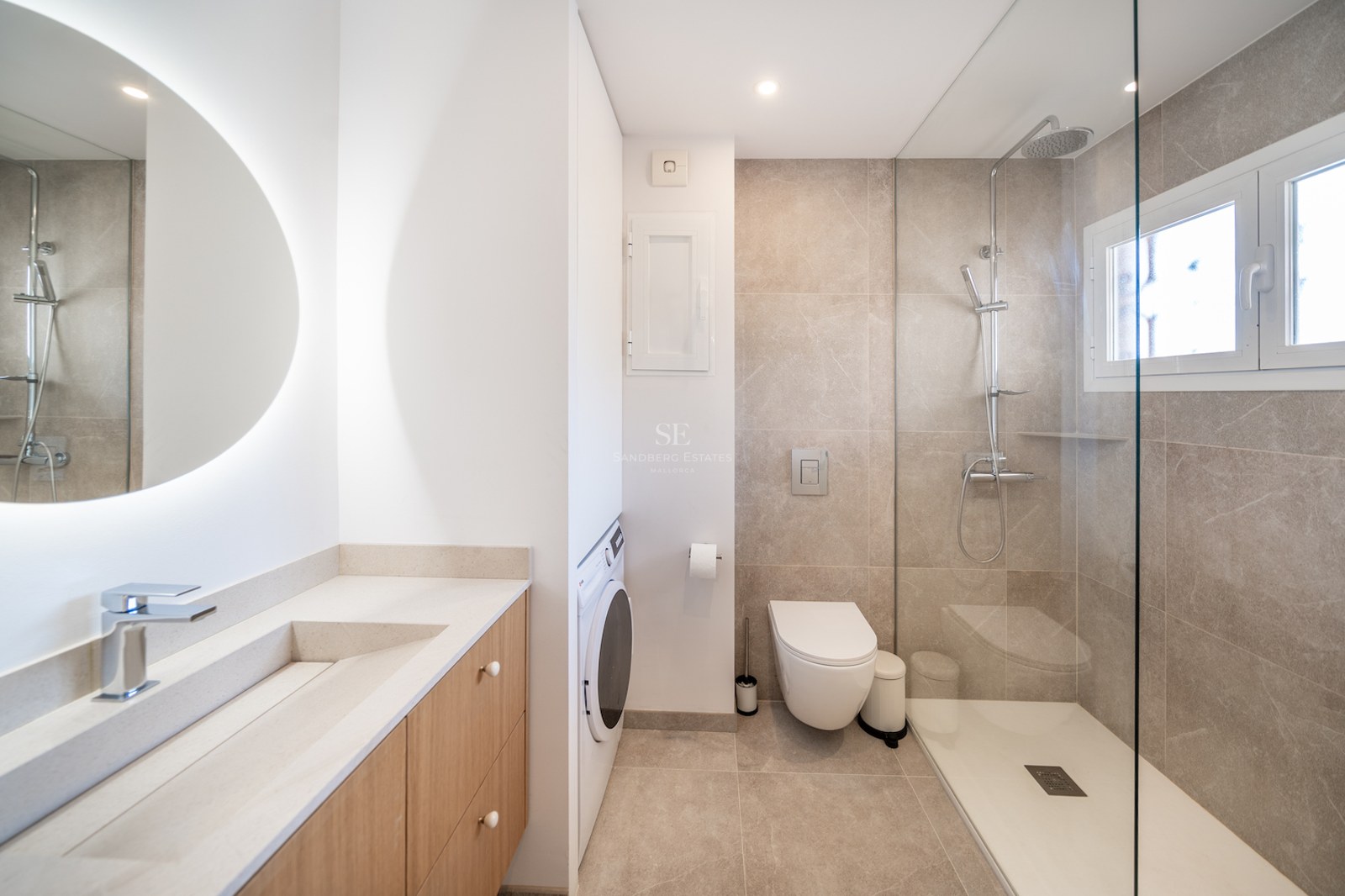 Salle de bains contemporaine avec douche à l'italienne, meuble en chêne clair et lave-linge intégré.