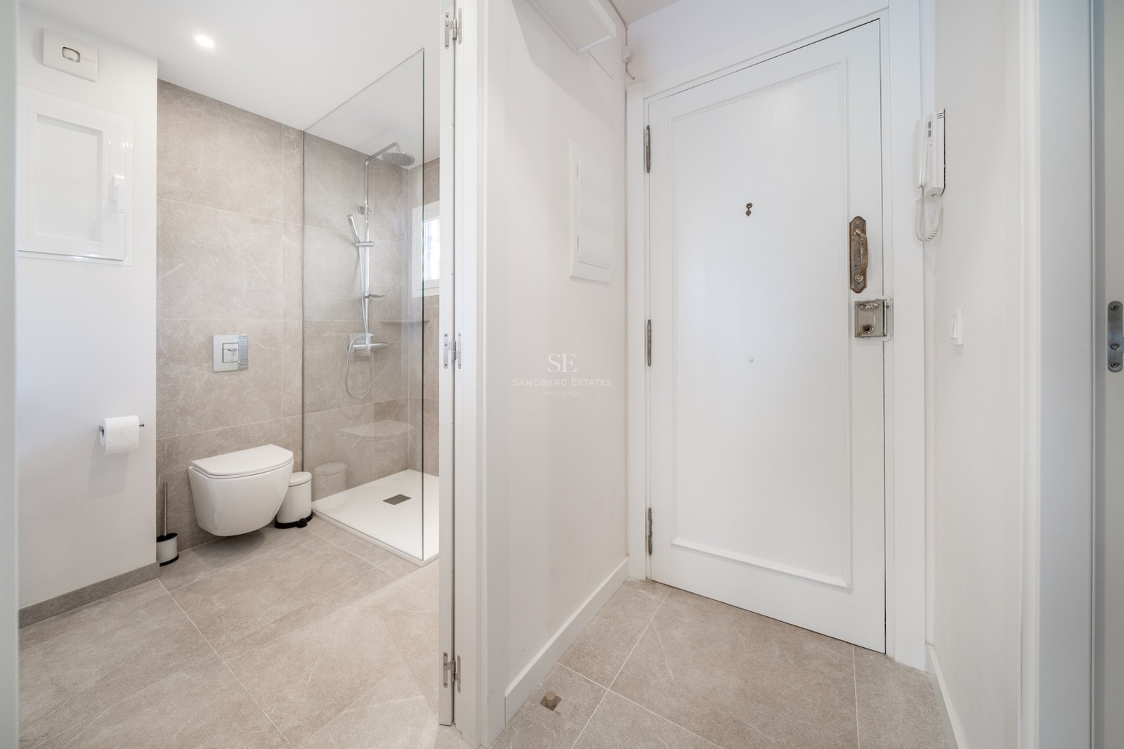 Salle de bains contemporaine avec douche vitrée, toilettes suspendues et carrelage en grès cérame tons sable.