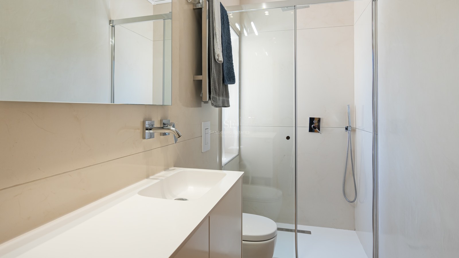 Salle de bains contemporaine avec carrelage crème, paroi de douche en verre et robinetterie chromée.