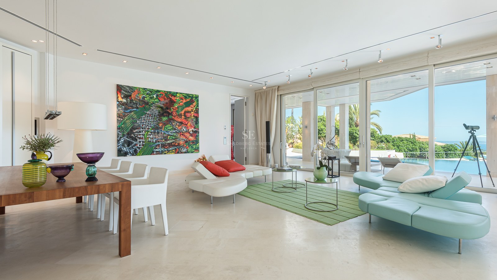 Bright living room with floor-to-ceiling glass doors opening to a terrace, pool, and sea view.