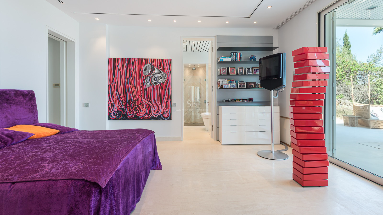 Modern bedroom with purple velvet bed, large abstract red painting, red sculpture, and glass doors to a terrace.