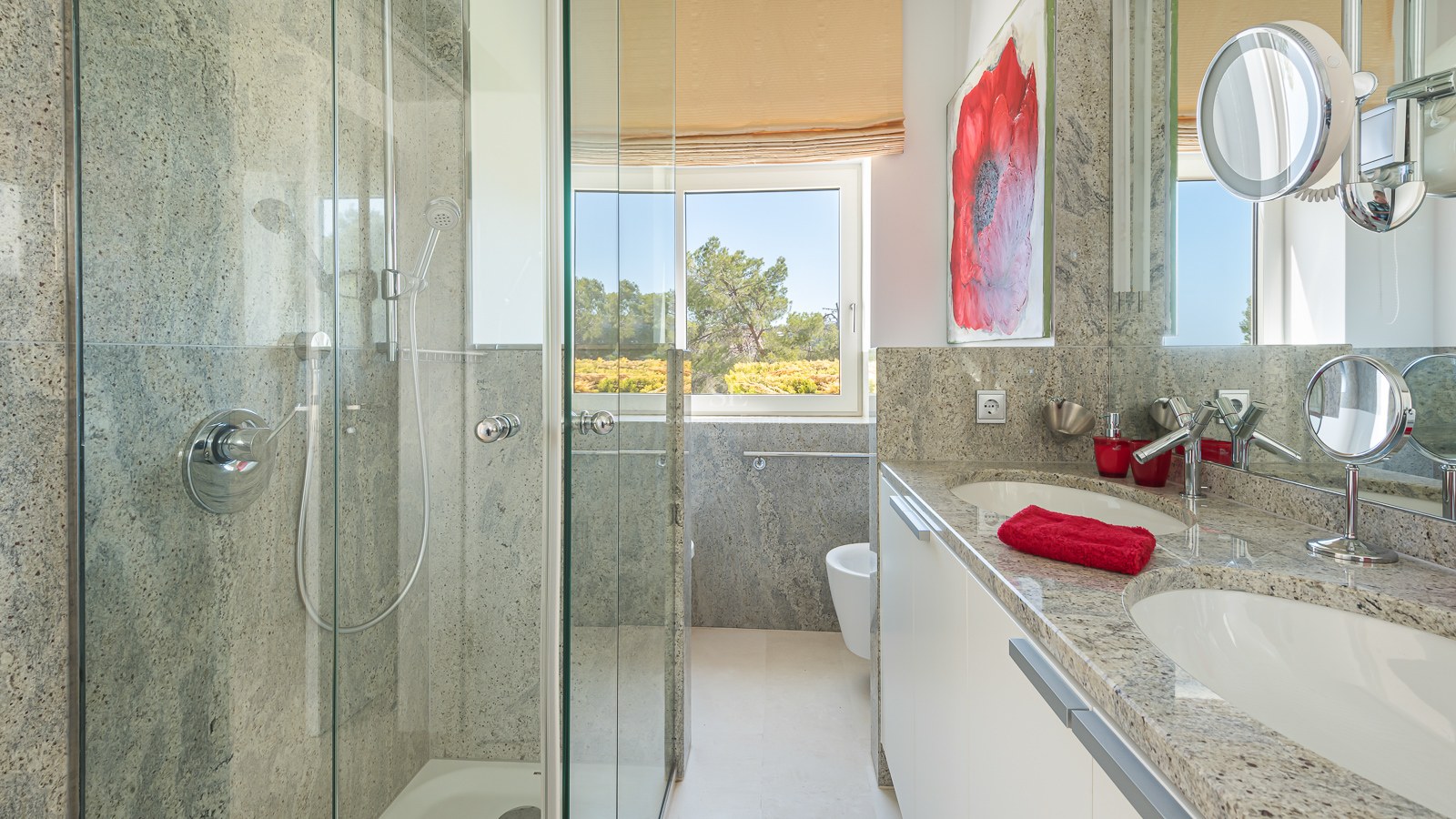 Modern bathroom featuring a granite double vanity, glass walk-in shower, and window with garden views.