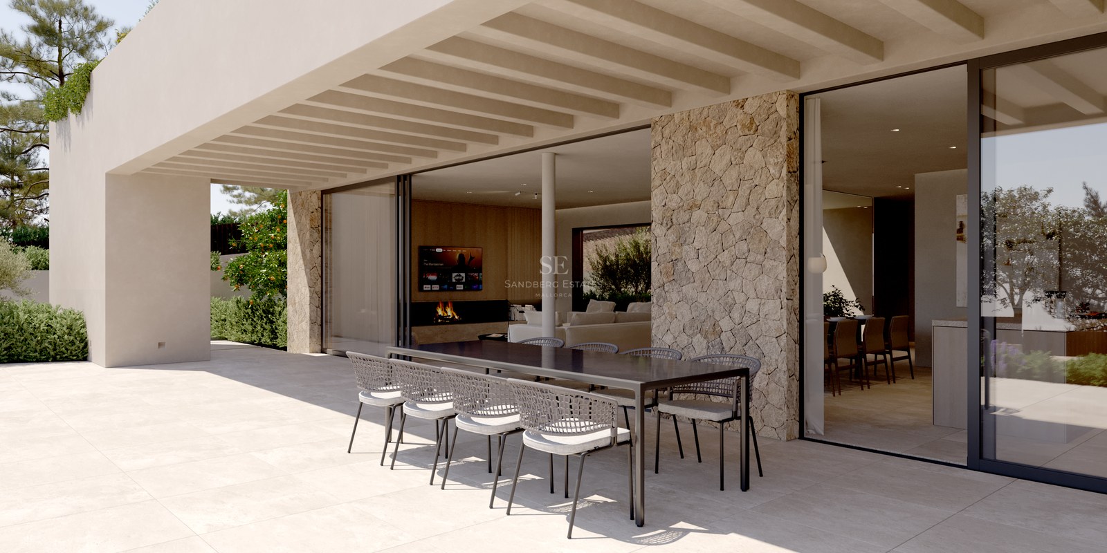 Terrasse moderne couverte avec table noire, chaises tressées, mur en pierre et grandes baies vitrées.
