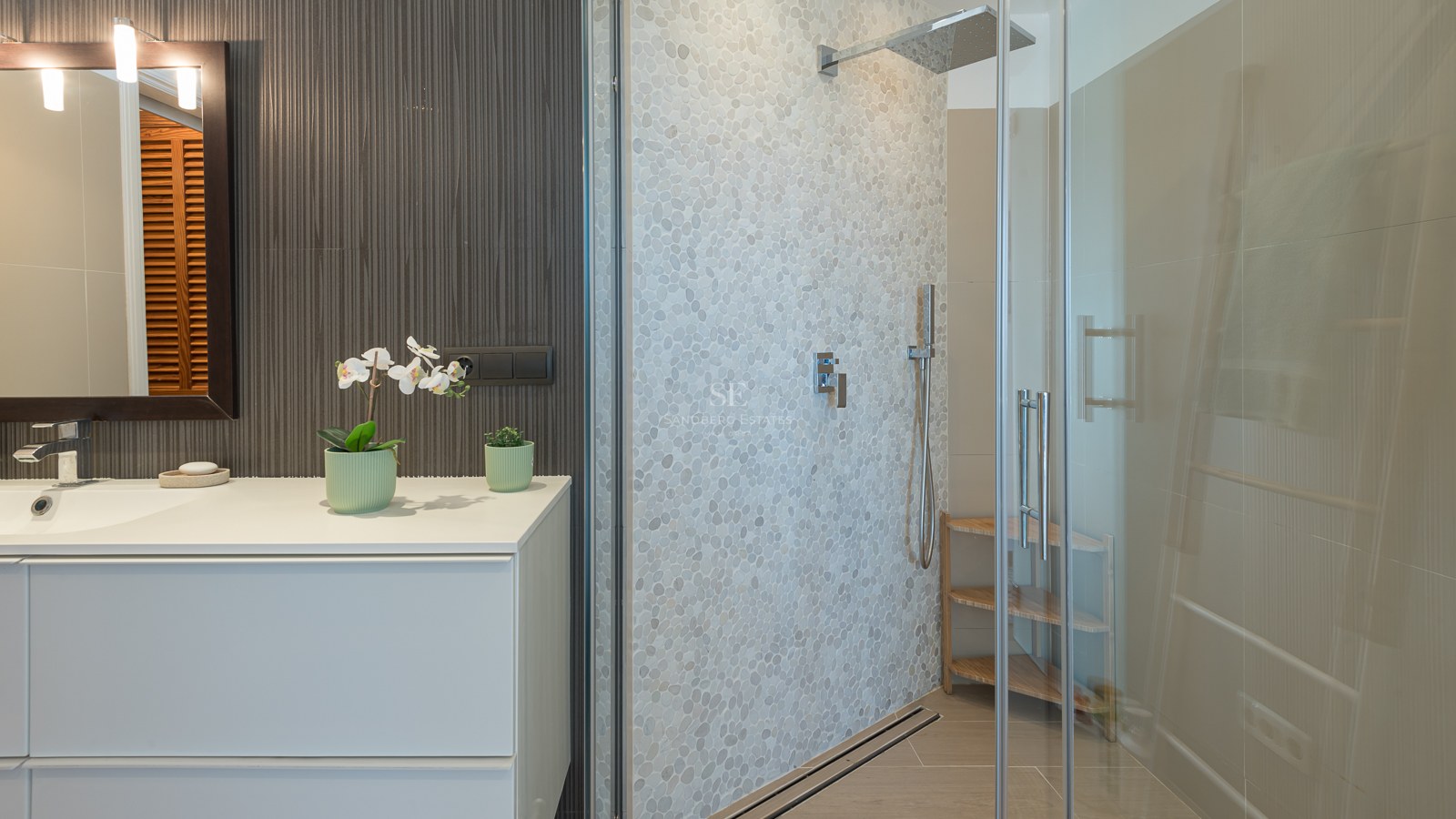 Salle de bain contemporaine avec meuble vasque blanc et douche en verre avec mur en galets texturés.