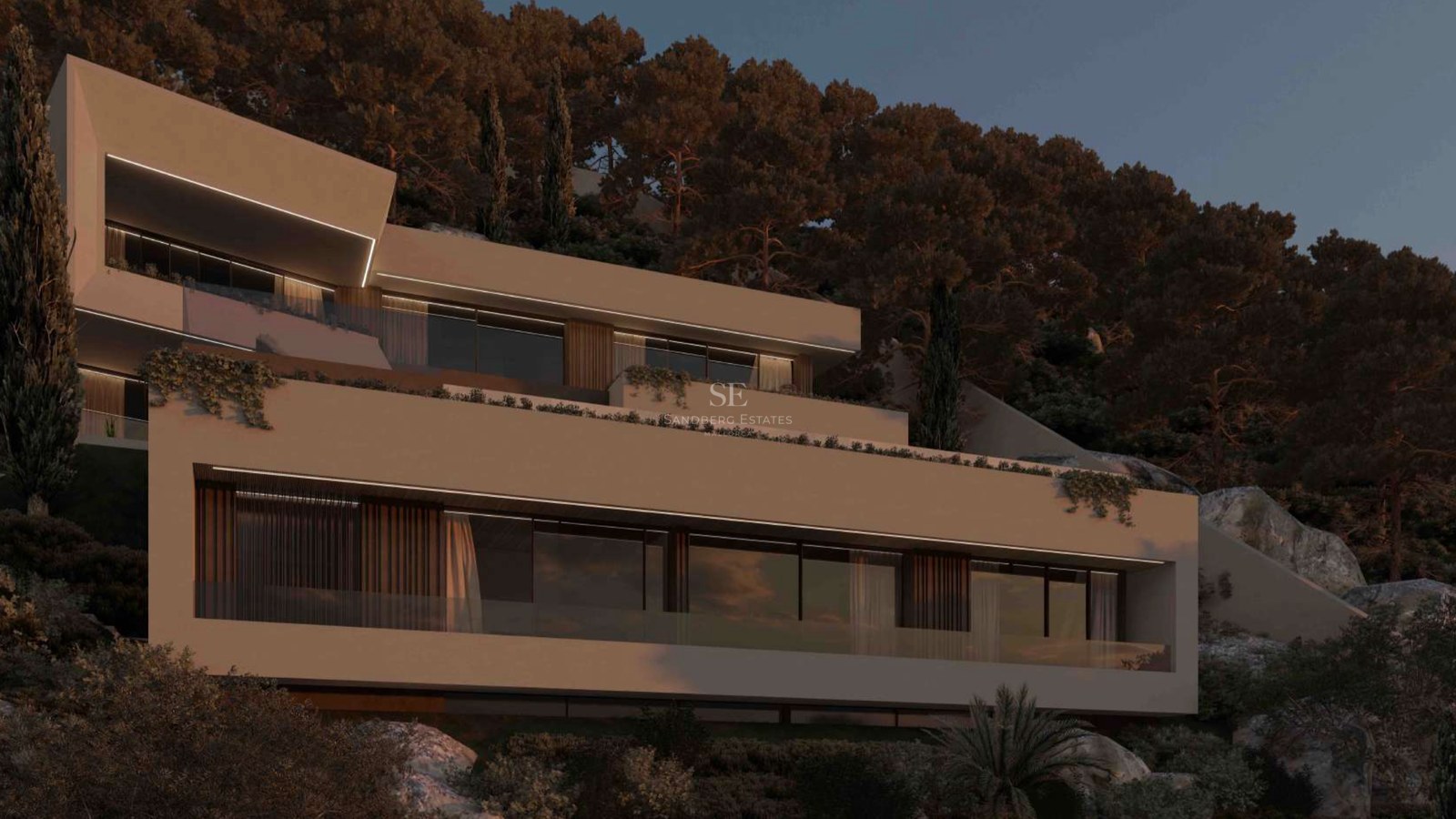 Villa contemporánea de varios niveles con terrazas de cristal integrada en una colina de pinos al anochecer.