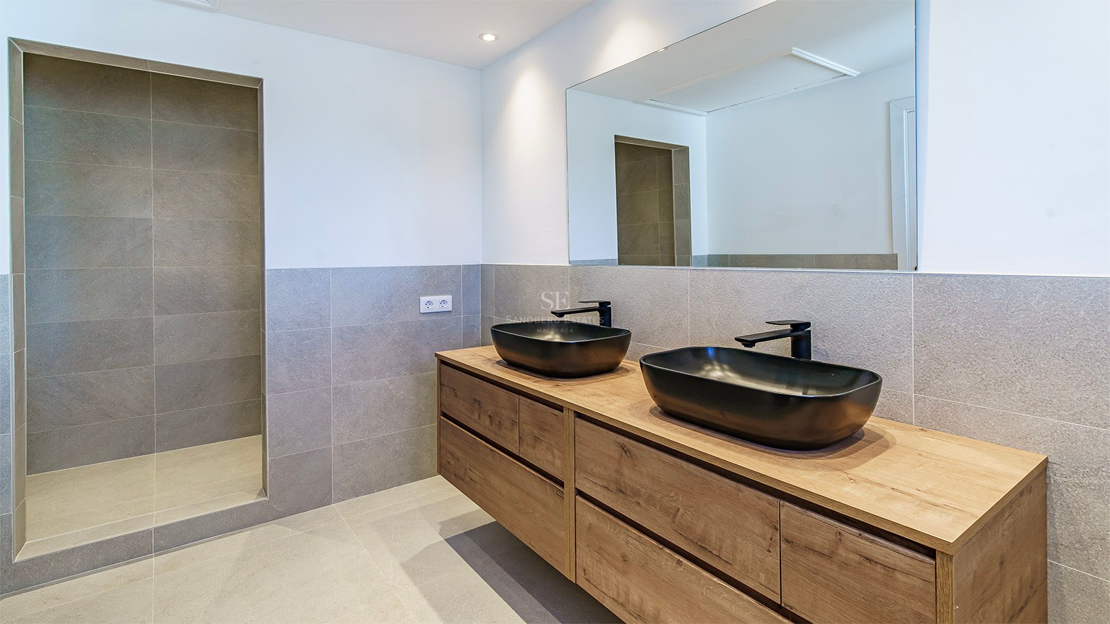 Salle de bains contemporaine avec carrelage gris, meuble en bois, vasques noires et douche à l'italienne.