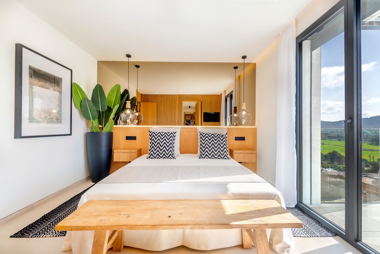 Dormitorio contemporáneo con cabecero de madera, lámparas de cristal y grandes ventanales con vistas al paisaje.