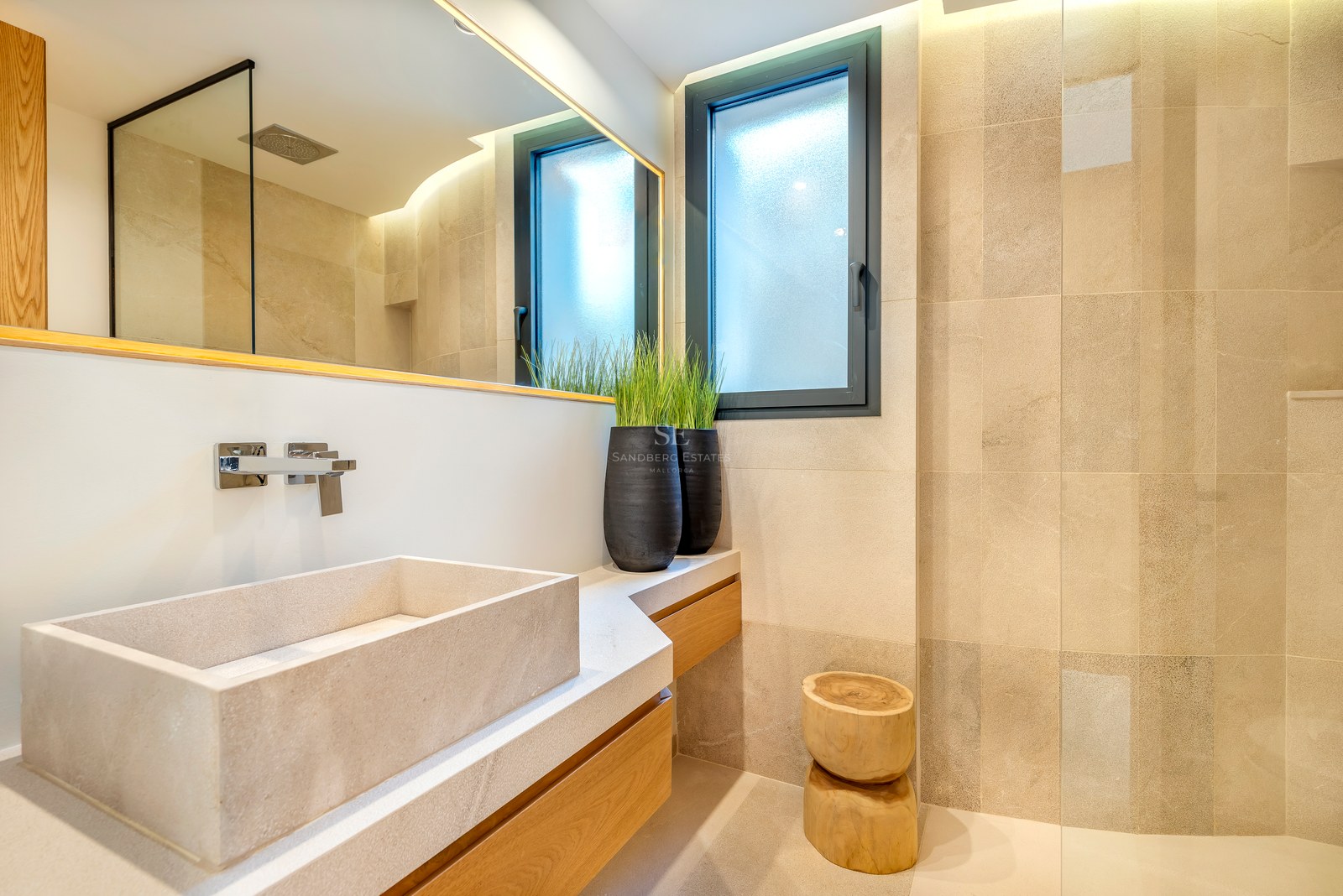 Baño contemporáneo con lavabo de piedra sobre mueble de madera, azulejos de piedra natural e iluminación suave.