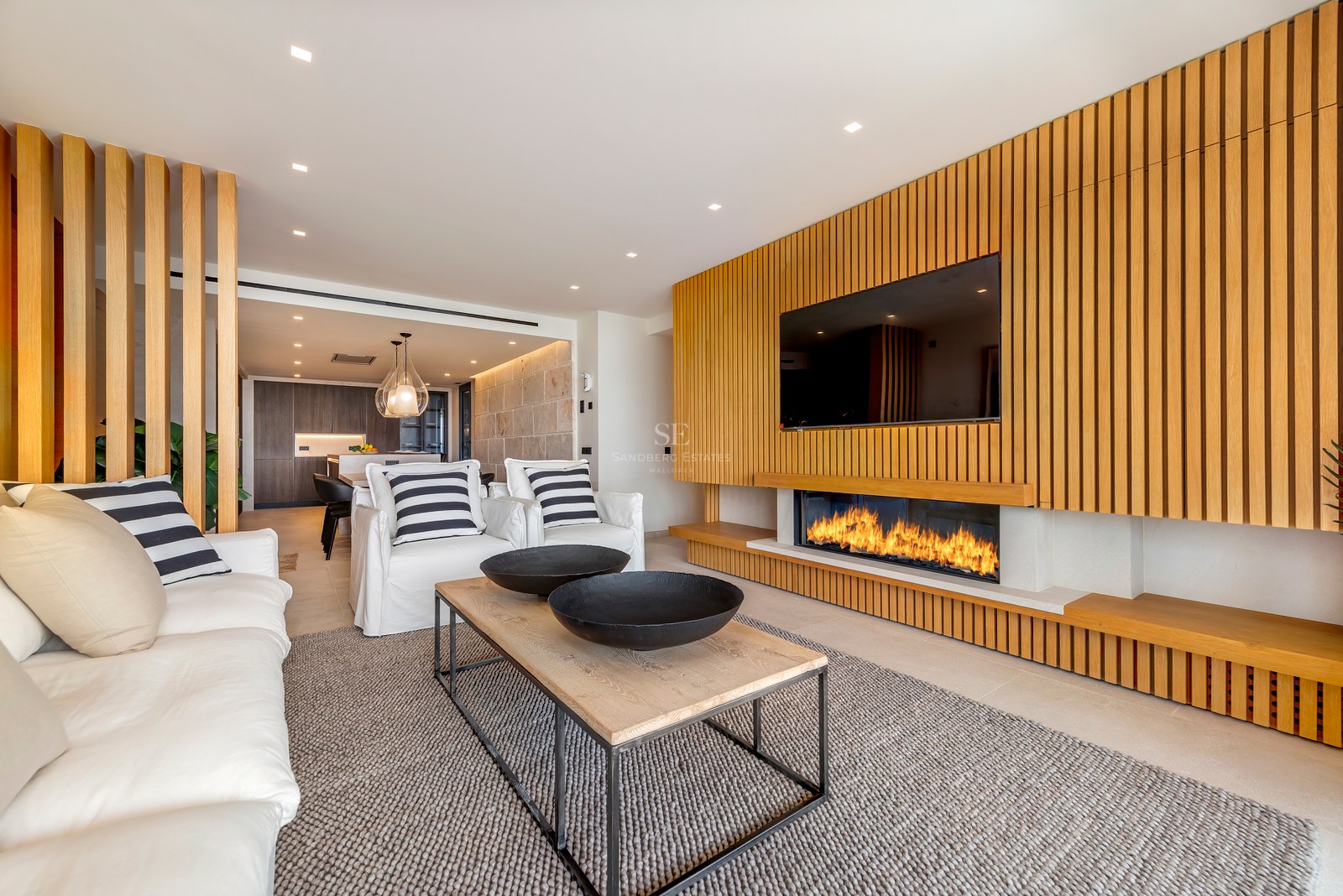 Salón contemporáneo con pared de listones de roble, chimenea lineal integrada y sofás blancos.