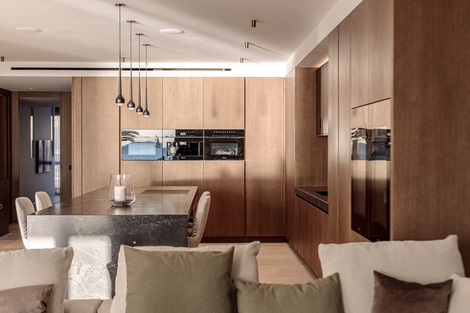 Modern kitchen featuring a dark marble island, light wood cabinetry, and high-end integrated appliances.