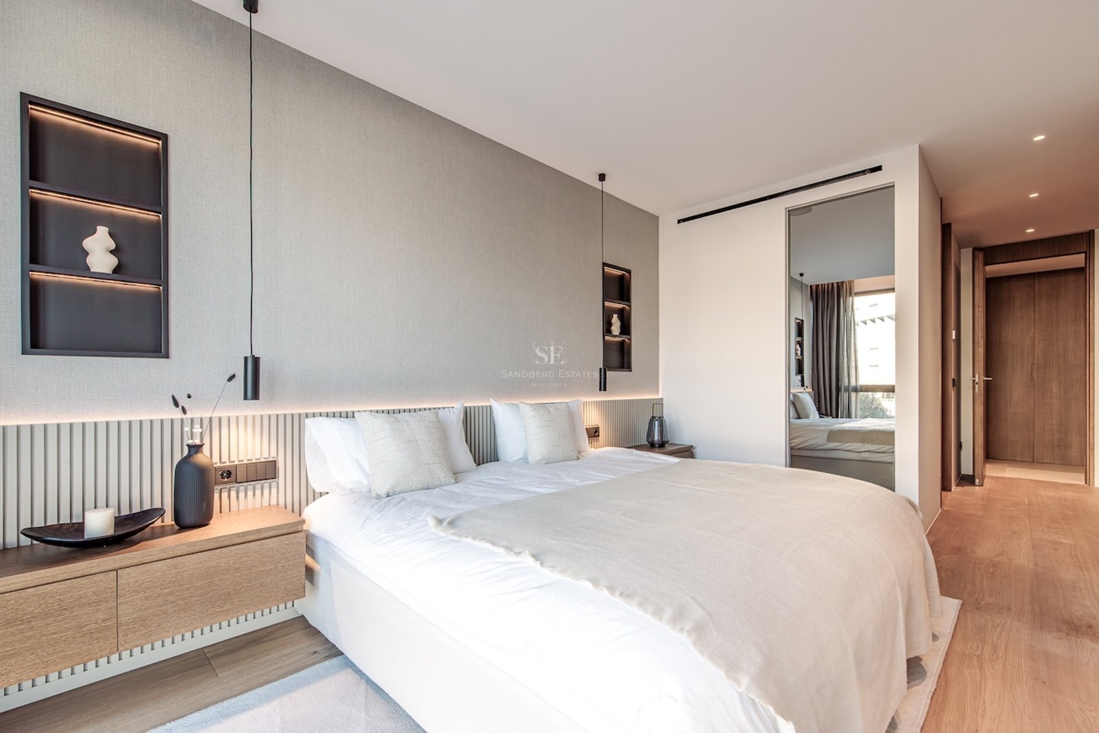 Modern master bedroom featuring a large bed, slatted wood headboard, integrated LED lighting, and neutral decor.