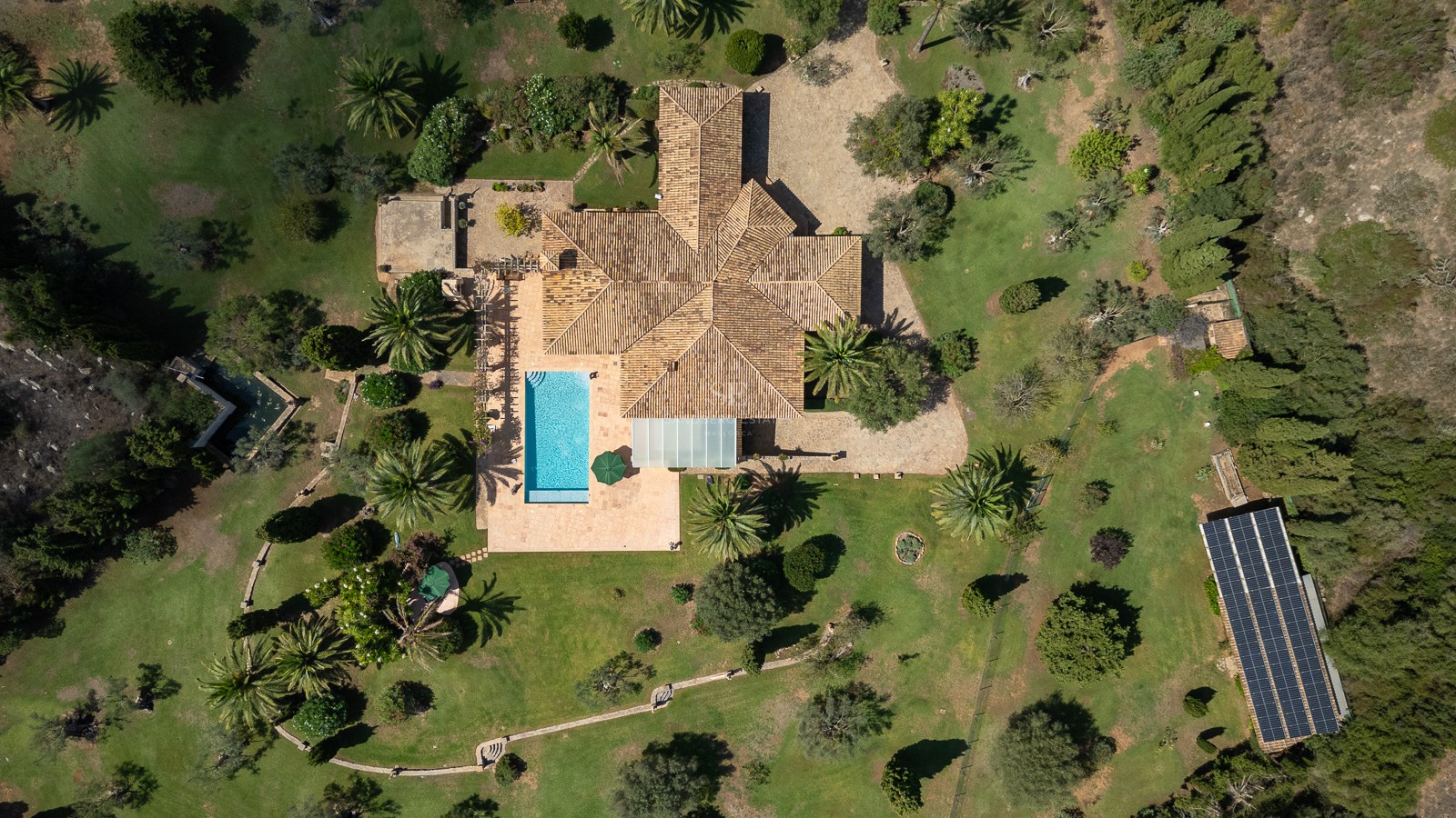 Draufsicht einer großen mediterranen Villa mit Pool, weitläufigen Gärten und Photovoltaikanlage.