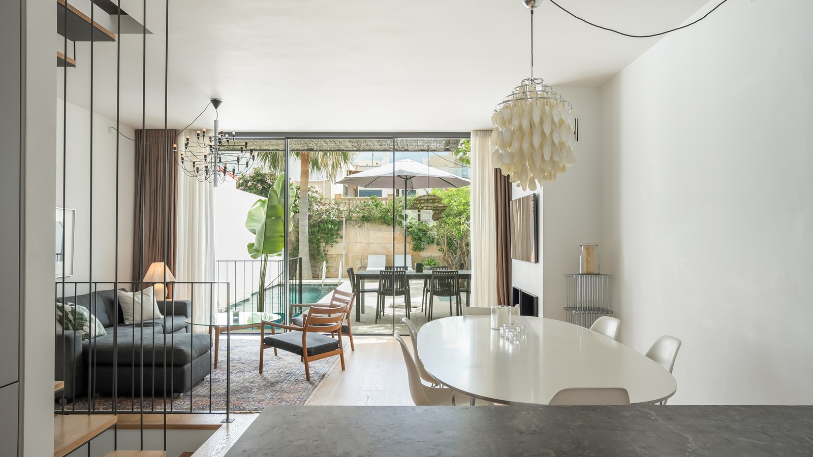 Salon et salle à manger lumineux avec baies vitrées s'ouvrant sur une piscine privée et une terrasse.